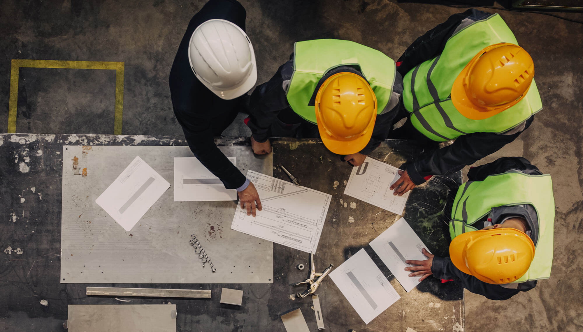 uomini con casco protettivo discutono ad un tavolo