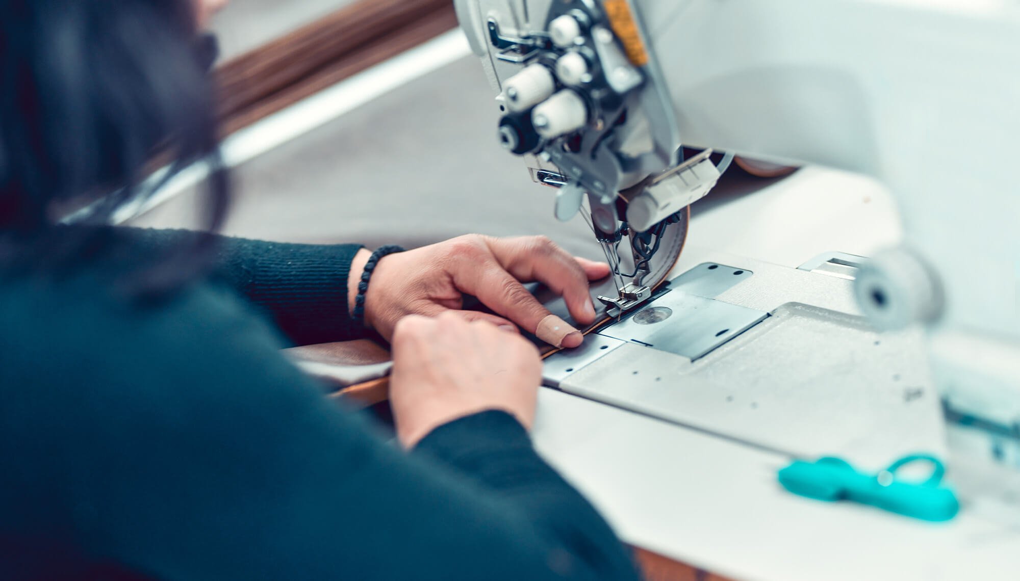 mani di donna mentre usano la macchina da cucire